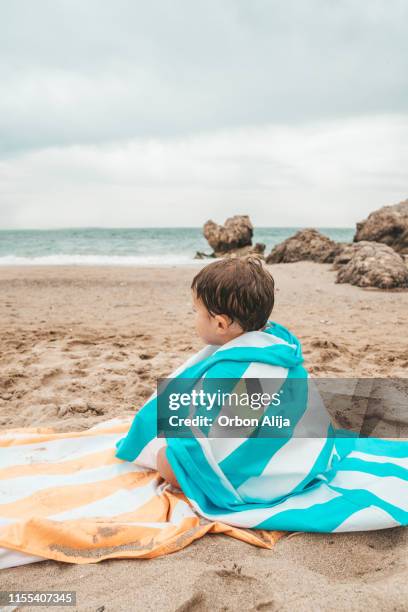boy playing in the rocks at the beach - striped towel stock pictures, royalty-free photos & images