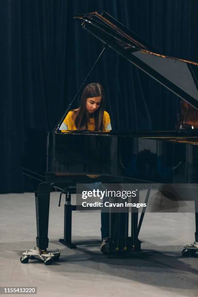 young woman is sitting behind piano and playing in concert hall. - pianist front stock pictures, royalty-free photos & images