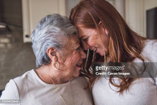 close up of senior woman and adult granddaughter touching foreheads - reencuentro fotografías e imágenes de stock