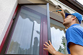 man installing mosquito net wire screen on terrace doors