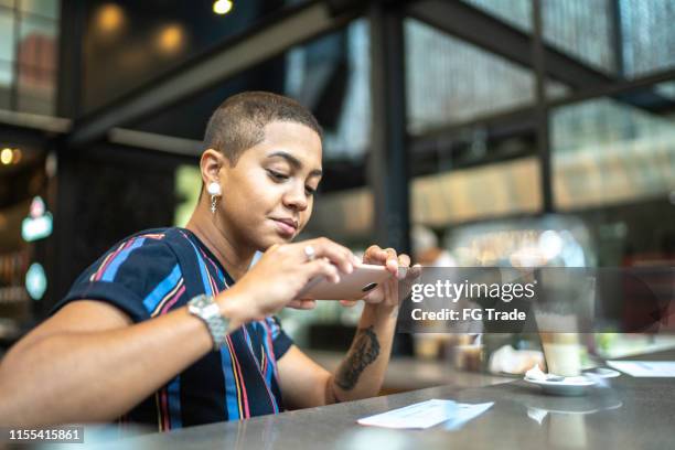 young woman depositing check by phone in the cafe - deposit slip stock pictures, royalty-free photos & images