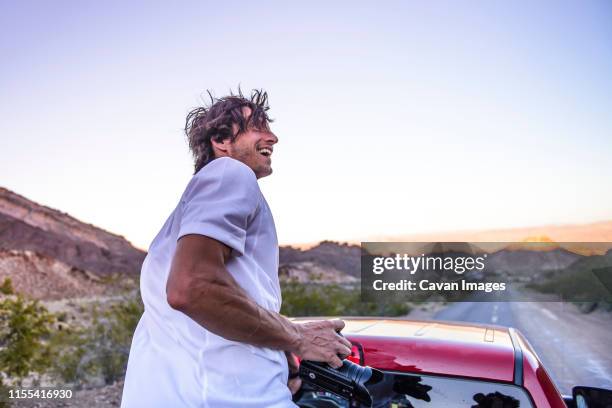 photographer laughing in back of truck holding dslr on road - filmmaker stock pictures, royalty-free photos & images