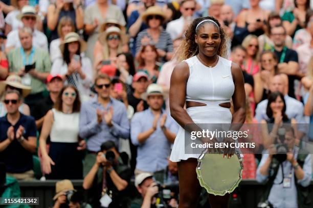 Player Serena Williams smiles as she poses with her trophy after being beaten by Romania's Simona Halep during their women's singles final on day...