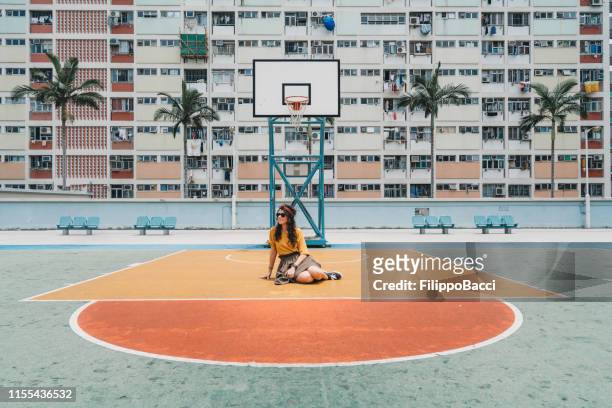 young adult influencer on a colourful basketball playground in hong kong city - woman yellow basketball stock pictures, royalty-free photos & images