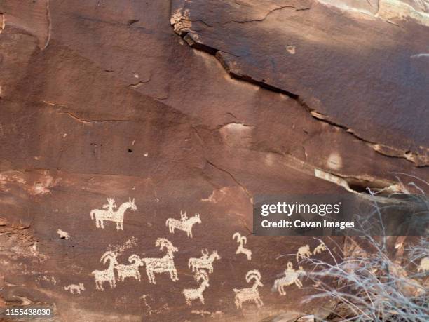 petroglyphs on a rock wall, arches national park. - pintura rupestre fotografías e imágenes de stock