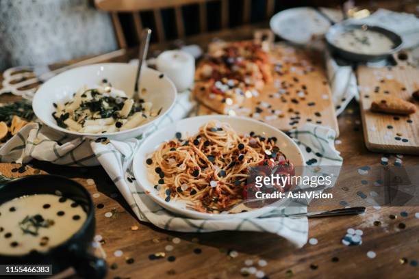 messy dining table with leftover food covered with confetti after party celebration - after party garbage stock pictures, royalty-free photos & images