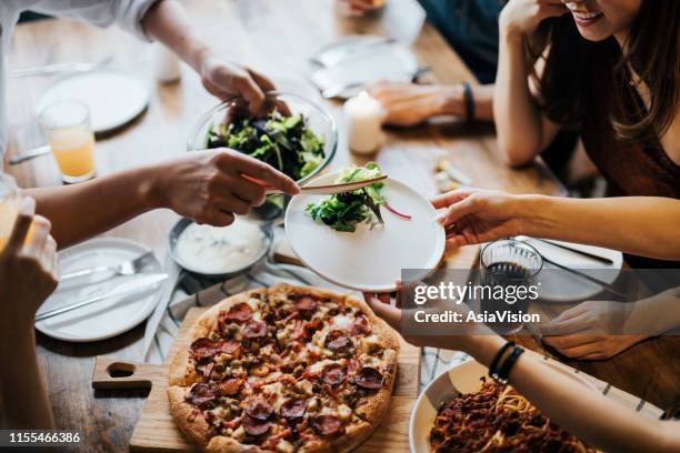 group of joyful young asian man and woman having fun, passing and sharing food across table during party - speed dating stock pictures, royalty-free photos & images