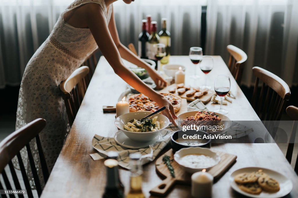 Young Asian woman setting the table and serving food and wine ready for party with friends at home