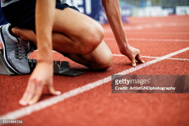 unrecognizable athlete preparing for start on running track. - beginnings stock pictures, royalty-free photos & images