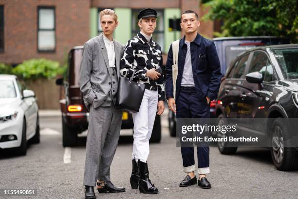 Guest wears an oversized grey suit, silver earrings, a white shirt and black boots, a guest wears a black cap, a black and white denim jacket, a...