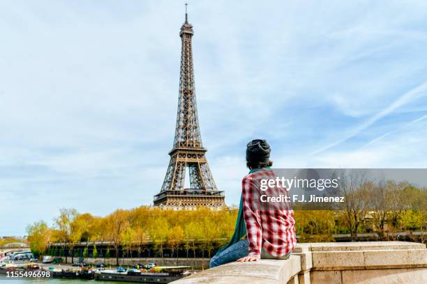 man sitting looking towards the eiffel tower - paris hiver photos et images de collection