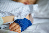 Sleeping sick child with peripheral venous line on his left hand in hospital