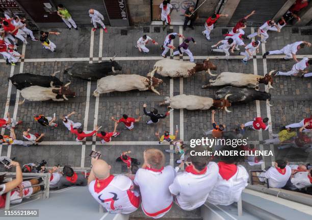 Revellers observe as participants run with Miura fighting bulls on the last bullrun of the San Fermin festival in Pamplona, northern Spain, on July...