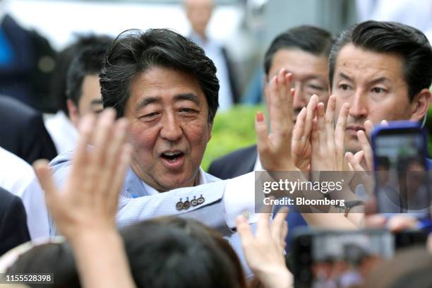 Shinzo Abe, Japan's prime minister and president of the Liberal Democratic Party , center, high-fives supporters during an election campaign rally in...