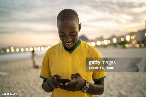 hombre negro escribiendo un mensaje en la playa - copacabana rio de janeiro fotografías e imágenes de stock