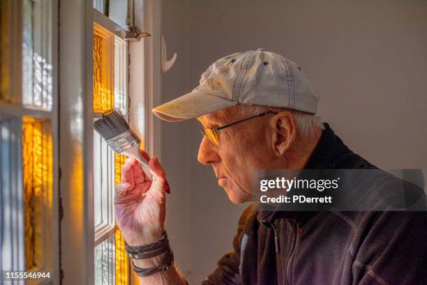 older man painting in his home renovation activity. - home renovations australia stock pictures, royalty-free photos & images