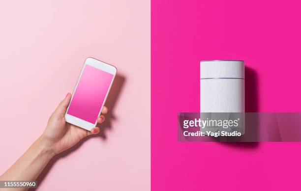 smart speaker and smart phone - hands holding smart phone fotografías e imágenes de stock