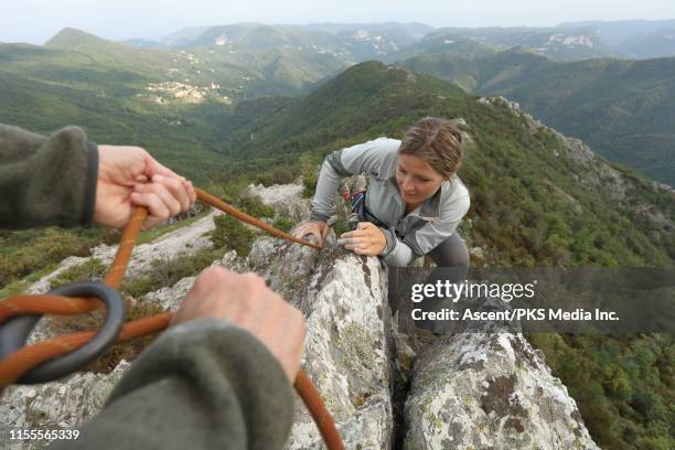 rock climber provides belay for companion, on ridge - zekeren stockfoto's en -beelden