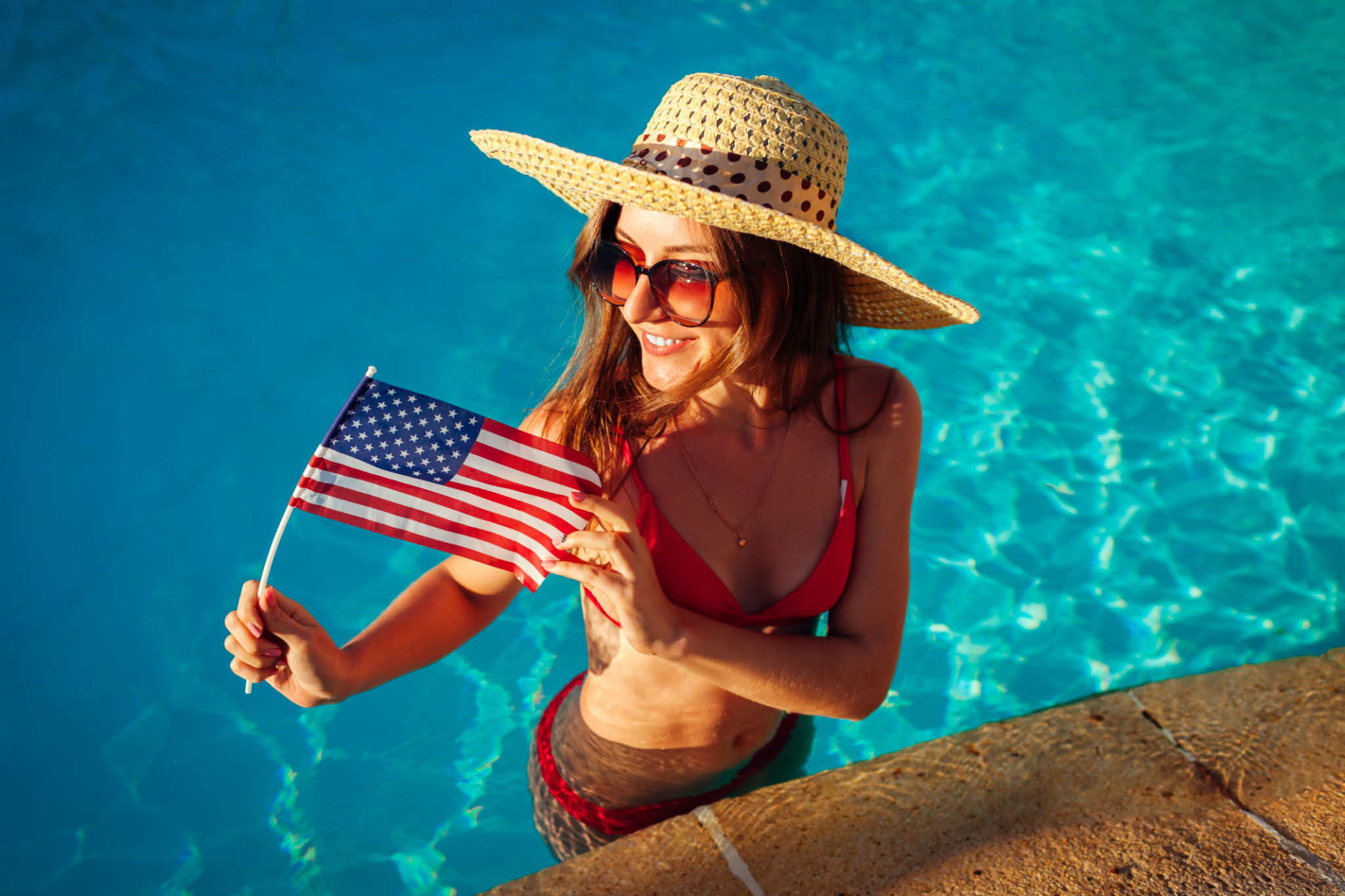 Sexy young woman holding USA flag in swimming pool. Celebrating Independence day of America Sexy young woman holding USA flag in swimming pool. Celebrating Independence day of America