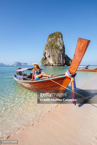 beautiful asian woman sitting on boat, railay, thailand - long tail boat stock-fotos und bilder