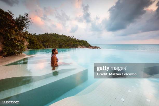 beautiful woman in an infinity pool at sunset, thailand - pool mit gegenströmung stock-fotos und bilder