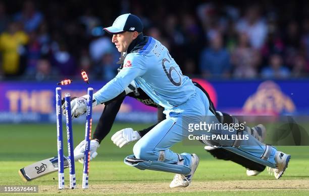 England's Jos Buttler knocks te bails off the stumps to take the wicket of New Zealand's Martin Guptill in the super over to win the 2019 Cricket...