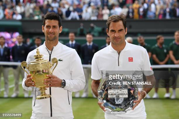 Serbia's Novak Djokovic poses with the winner's trophy and Switzerland's Roger Federer holds the runners up plate during the presentation after the...