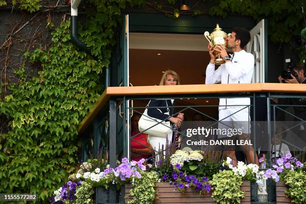 Serbia's Novak Djokovic poses with the winner's trophy on the balcony of the club house after beating Switzerland's Roger Federer during their men's...