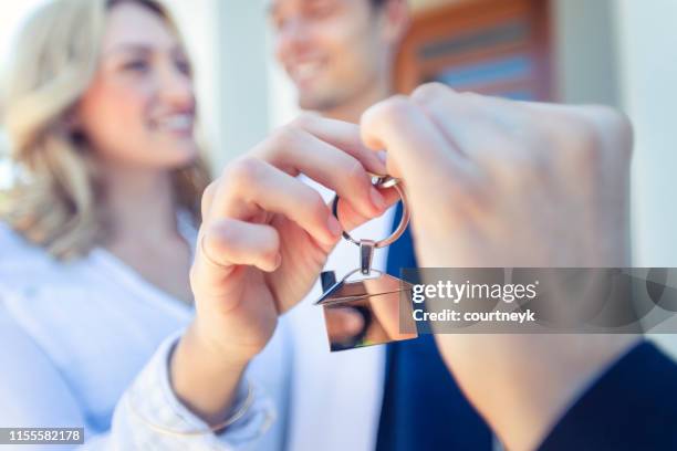 real estate agent giving a young couple the key to their new house - estate agent sign stock pictures, royalty-free photos & images