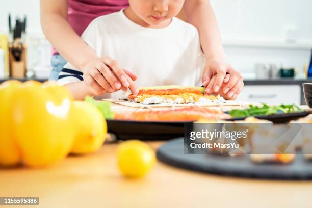 young boy learning to make sushi hand roll - nori stock pictures, royalty-free photos & images