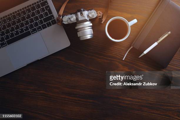a laptop, a cup of tea, a camera and a notebook lie on a dark wooden table. the workplace of a photographer or a freelancer. copy paste for text. - office work flat lay stock pictures, royalty-free photos & images