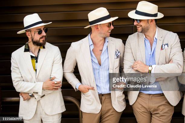 Gentlemen, wearing light color suits and straw hats, are seen during Pitti Immagine Uomo 96 on June 12, 2019 in Florence, Italy.