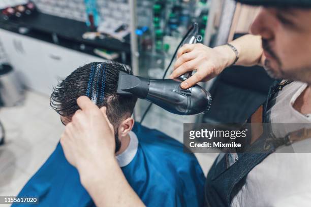 professional barber blow drying the hair of young man - hair dryer stock pictures, royalty-free photos & images
