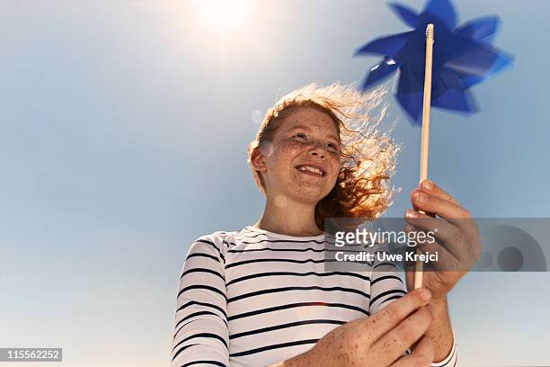 girl on beach holding toy windmill, portrait - elf toy stockfoto's en -beelden