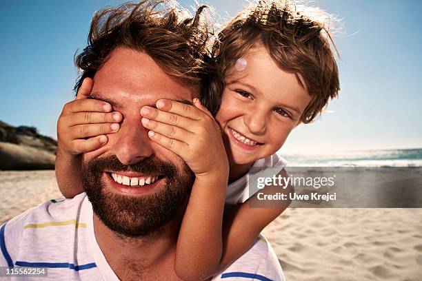 boy (4-5) with hand over fathers eyes, close up - hands covering eyes stock pictures, royalty-free photos & images