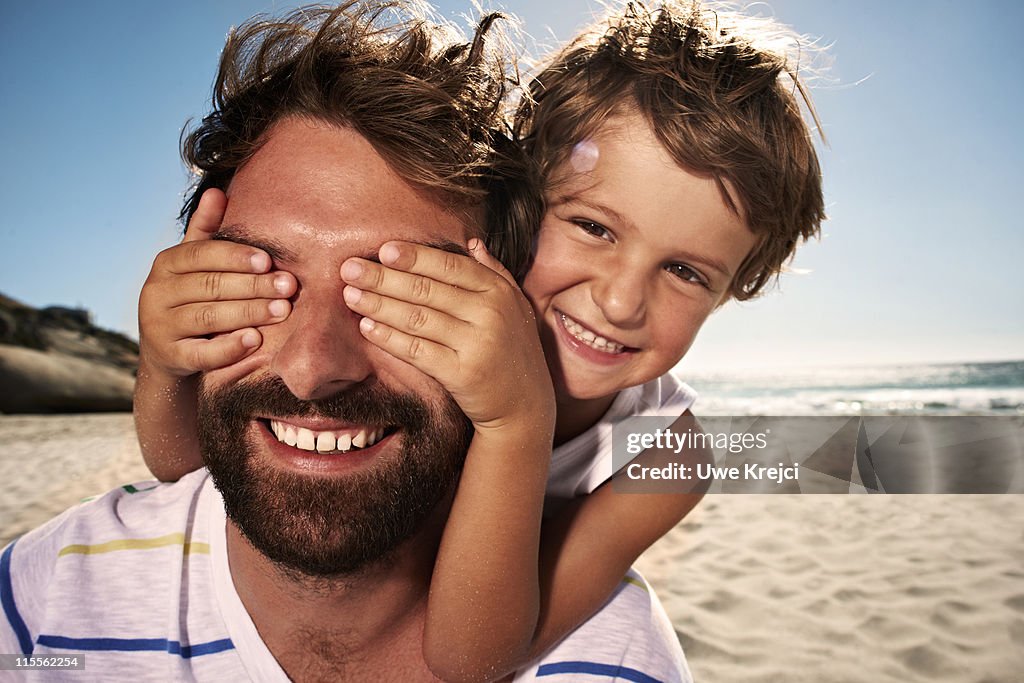 Boy (4-5) with hand over fathers eyes, close up
