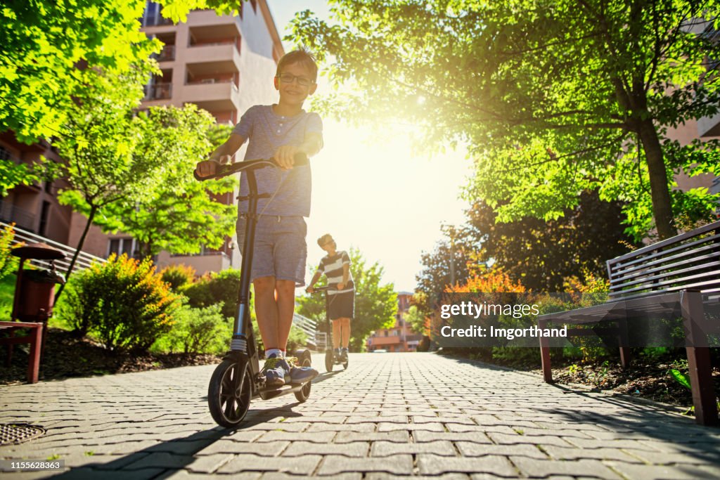 Kinderen rijden scooters in de stad woonwijk.