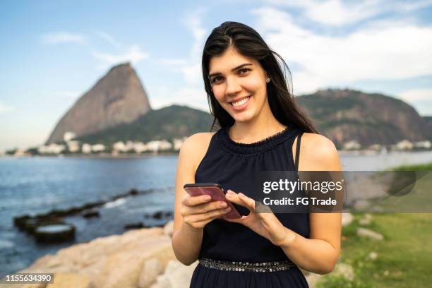 leende kvinna tittar på kameran och hålla en telefon - urca rio de janeiro bildbanksfoton och bilder