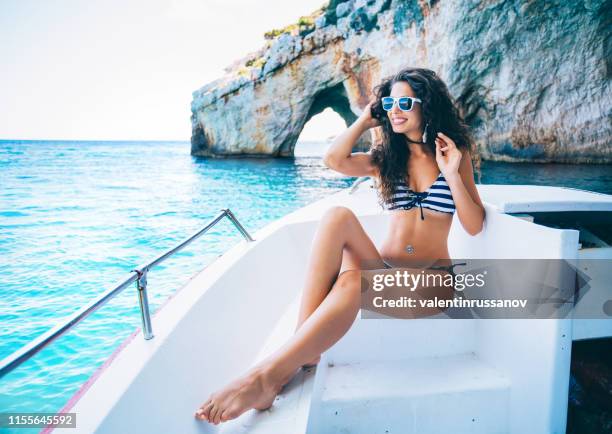 beautiful woman sitting on yacht and enjoying the sun in zakynthos greece - navagio beach - motor yacht stock pictures, royalty-free photos & images