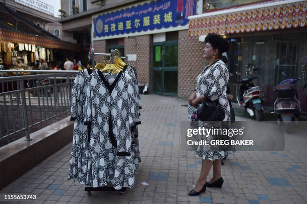 This photo taken on June 4, 2019 shows a Uighur vendor waiting for customers for her dresses outside a market in Kashgar, in China's western Xinjiang...