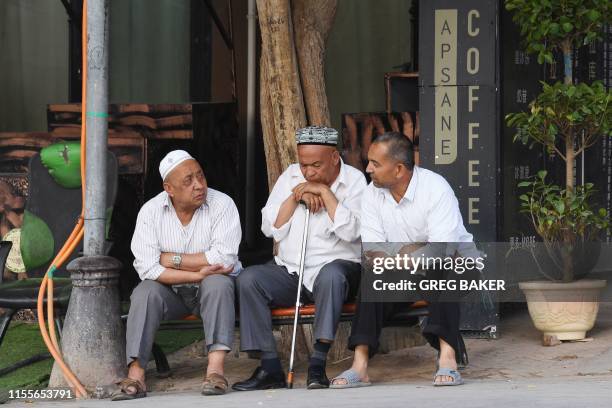 This photo taken on June 4, 2019 shows Uighur men resing in front of a coffee bar in the restored old city area of Kashgar, in China's western...