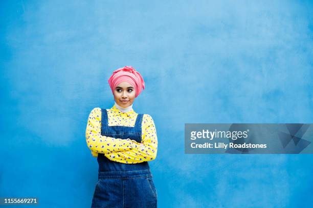 young muslim woman against a blue wall outdoors - young muslim stockfoto's en -beelden