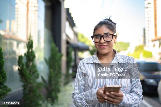 verticale d'une femme latine utilisant le téléphone portable dans la rue - femme perou photos et images de collection