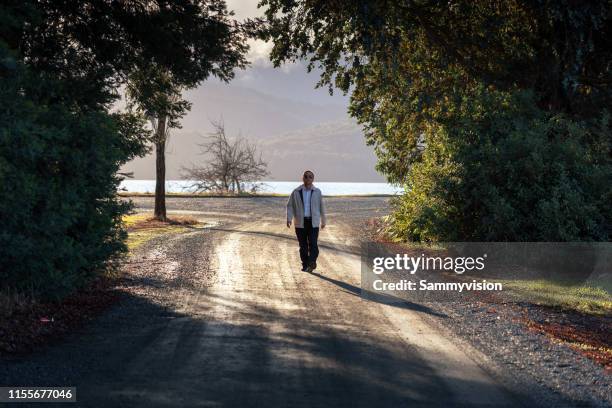 a man is walking through the village, under the sunlight - te anau stock pictures, royalty-free photos & images