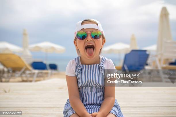 cool klein meisje met een zonnebril maken grappige gezichten - kids swimsuit models stockfoto's en -beelden