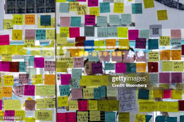 Woman posts a message to a Lennon Wall at the glass wall of an arcade in the Mong Kok district of Hong Kong, China, on Thursday, July 11, 2019....