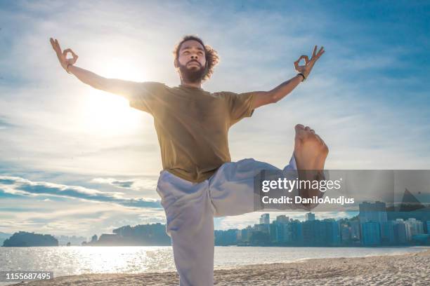 man doing yoga on the beach - yoga instructor stock pictures, royalty-free photos & images