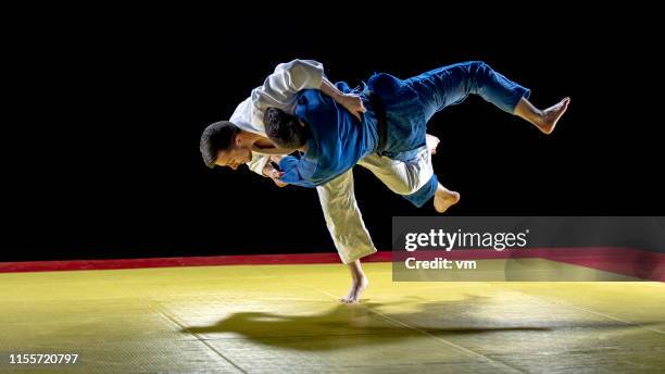 judoka wirft seine partnerin zu boden - judo stock-fotos und bilder
