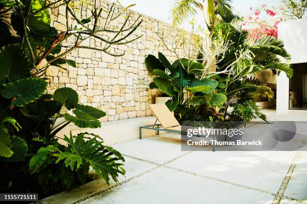 view of lounge chair in garden area of tropical spa - stone wall garden stock pictures, royalty-free photos & images