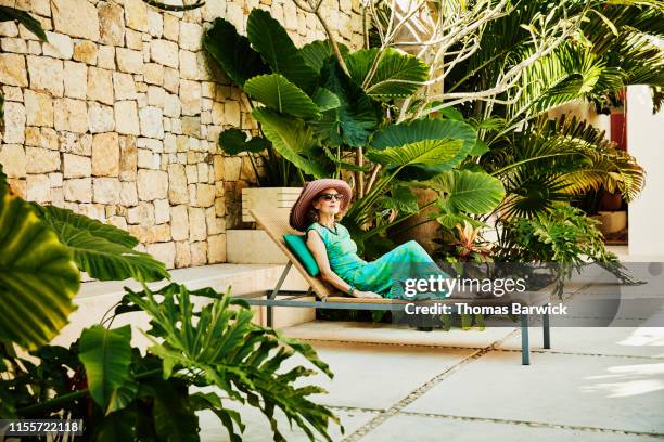 senior woman relaxing in lounge chair at tropical spa - blue dress stock pictures, royalty-free photos & images